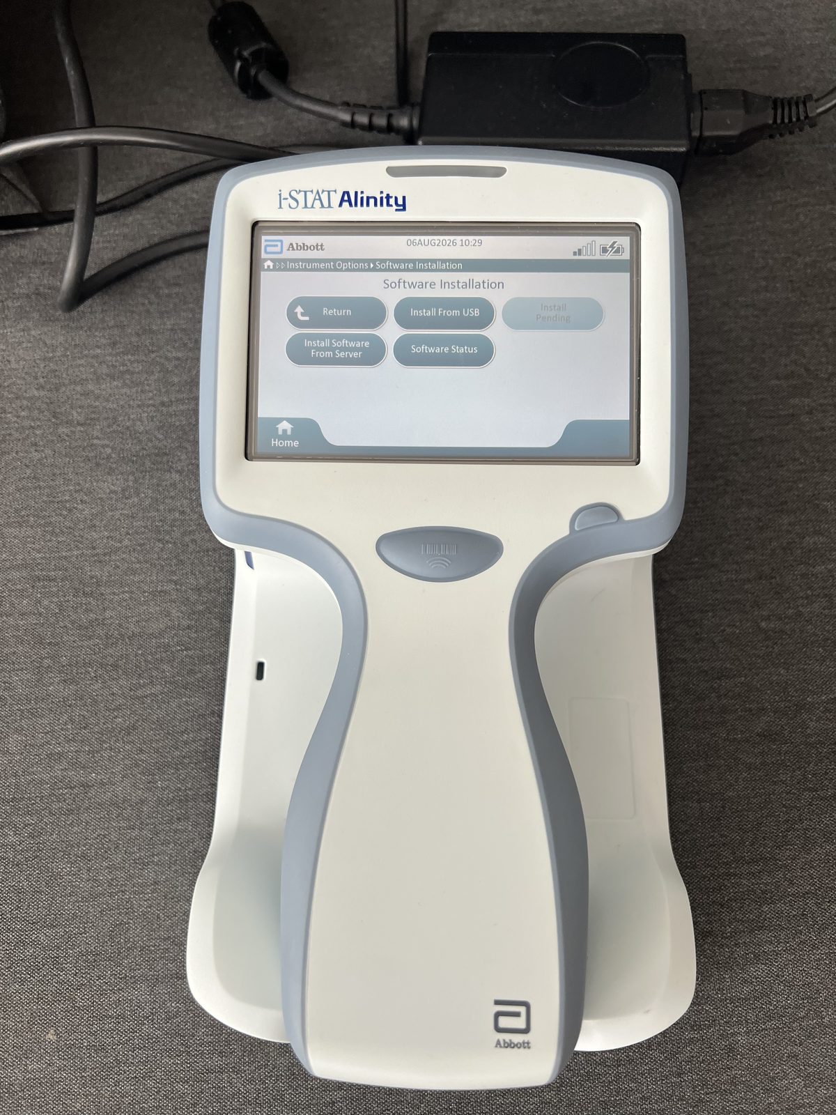 i-STAT Alinity docked in the charging base station, screen dated 6 August 2026